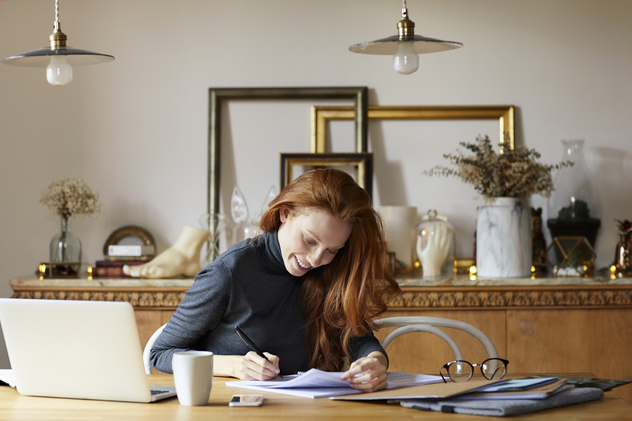 Woman writing on documents at table
